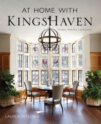 Light interior space, wood floor, table and chairs in front of large stained glass window, AT HOME WITH KINGSHAVEN in black font above.