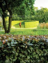 Landscaped garden with topiary hedge and sculpture of face, INTERSECTION OF NATURE AND ART, in small white font above centre cover.