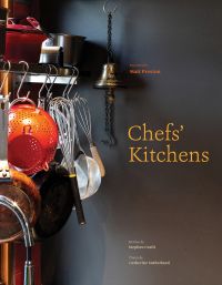 Row of kitchen utensils: orange colander, hand whisks, pans and a sieve, on cover of 'Chefs' Kitchens', by Images Publishing.