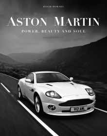 White Aston Martin V12 Vanquish on road, mountains behind, 'ASTON MARTIN', in white font above, by The Images Publishing Group.