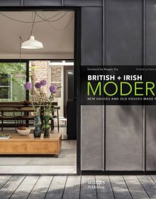 Book cover of British + Irish Modern: New Houses and Old Houses Made New with a large open door to interior, low table with purple alliums in vase, hanging light fittings. Published by Images Publishing.