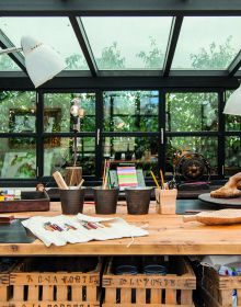 Artist sitting in wood studio, tree hammock in foreground, on green cover, Creative Spaces for Creative Ideas in white font above.