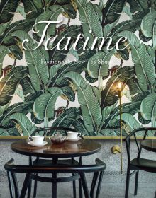 Tea shop interior, table and chairs with white cups, saucers and glass teapot, tropical green wallpaper behind, Teatime in white font above.