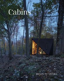 Book cover of Cabins: Escape to Nature, with modern cabin in a forest, with interior lights on. Published by Images Publishing.