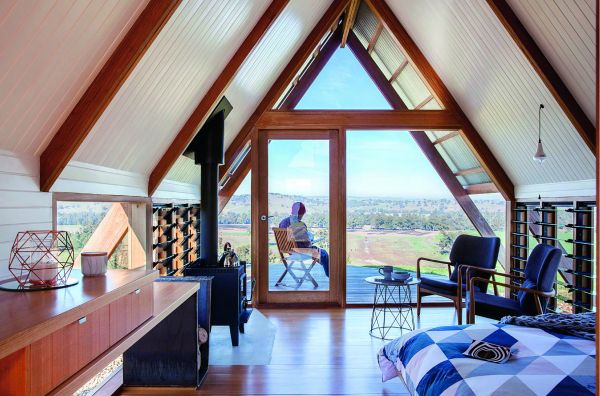 Book cover of Cabins: Escape to Nature, with modern cabin in a forest, with interior lights on. Published by Images Publishing.