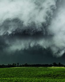 Atmospheric dark storm cloud above landscape, sun light to far left, FIERCE BEAUTY Storms of the Great Plains in white font above.