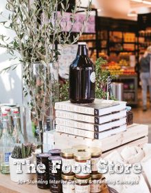 Table full of jars of artisan food products, in retail food interior, The Food Store in white distressed font below.