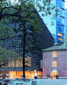 Building façade with dark grey modern exterior cover, ARCHITECTURE CHINA RE/DEFINE TRADITION in beige and white font above and below.