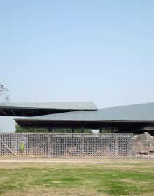 Building façade with dark grey modern exterior cover, ARCHITECTURE CHINA RE/DEFINE TRADITION in beige and white font above and below.