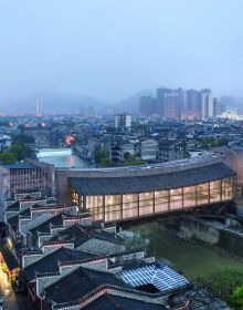 Building façade with dark grey modern exterior cover, ARCHITECTURE CHINA RE/DEFINE TRADITION in beige and white font above and below.