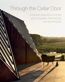 Outdoor view of modern architectural winery with vineyards in the distance and Through the Cellar Door in fine black font above