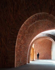 Interior wall and staircase of Jingdezhen Imperial Kiln Museum, visitor walking down corridor, by Images Publishing.