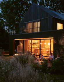 Book cover of Susan Redman's Modern Homes in Black, with a black wooden lake house in Berlin, surrounded by a garden. Published by Images Publishing.