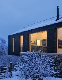 Book cover of Winter Homes: Stylish Living for Cool Climates, with a cabin obscured by snow-covered forest trees. Published by Images Publishing.